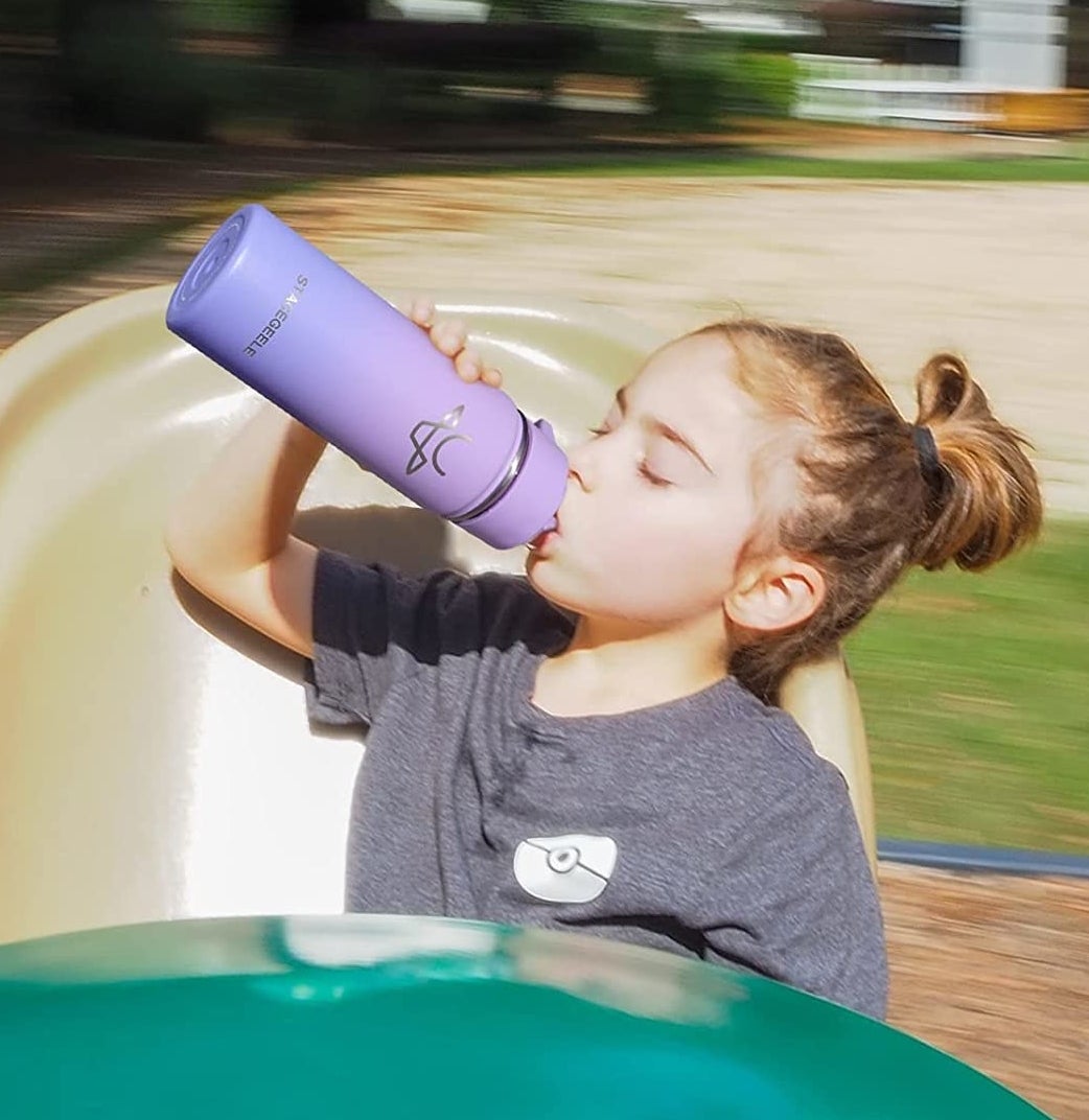 a kid sipping from the bottle while at the park