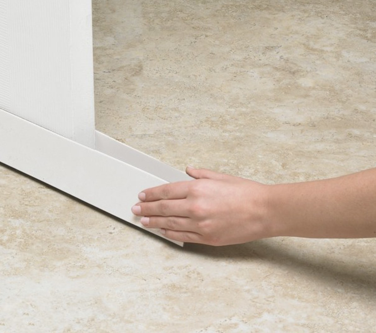 A hand installing the draft stopper under a door