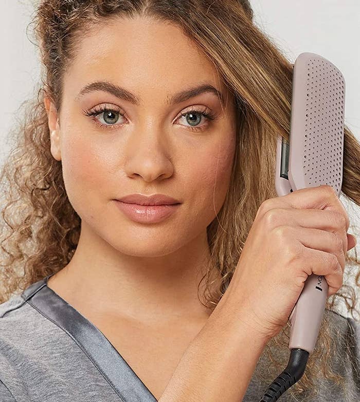 model using the flat iron to straighten their hair