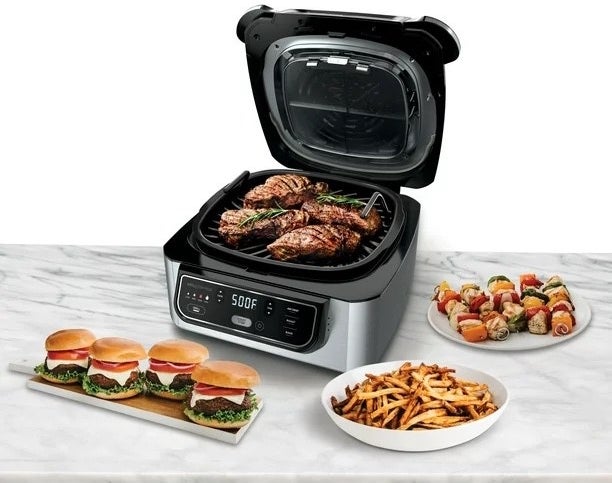 a silver and black indoor grill next to French fries, cheeseburgers, kebabs, and steaks