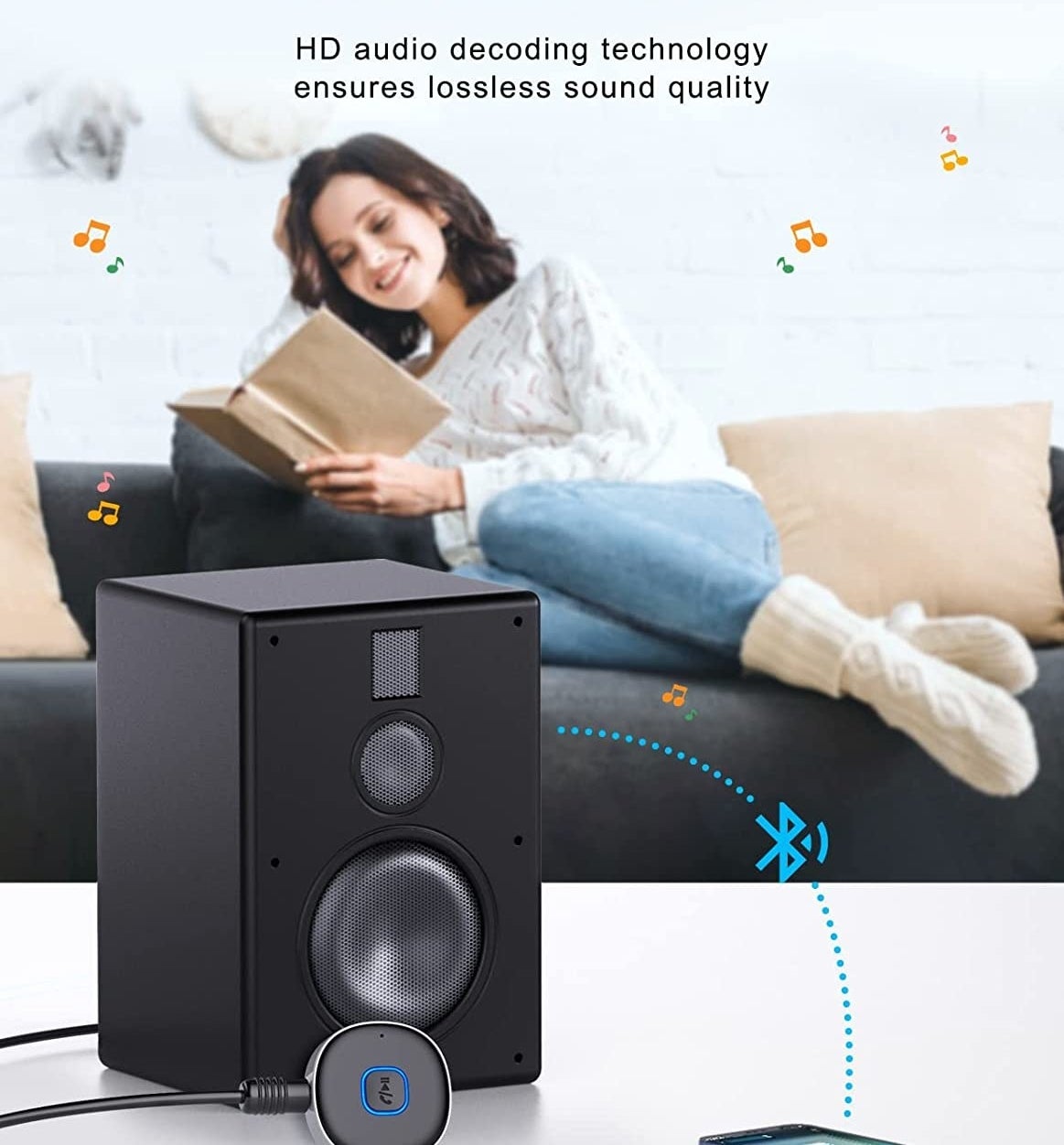 person sitting on the couch reading a book with the receiver connected to an old stereo