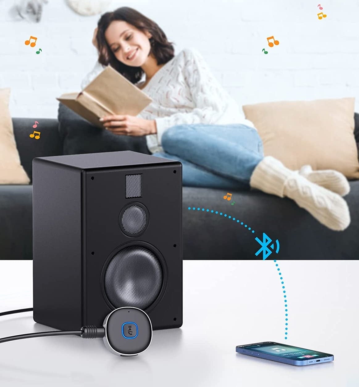 person sitting on the couch reading a book with the receiver connected to an old stereo