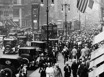 People walk through a busy city street in the 1920s
