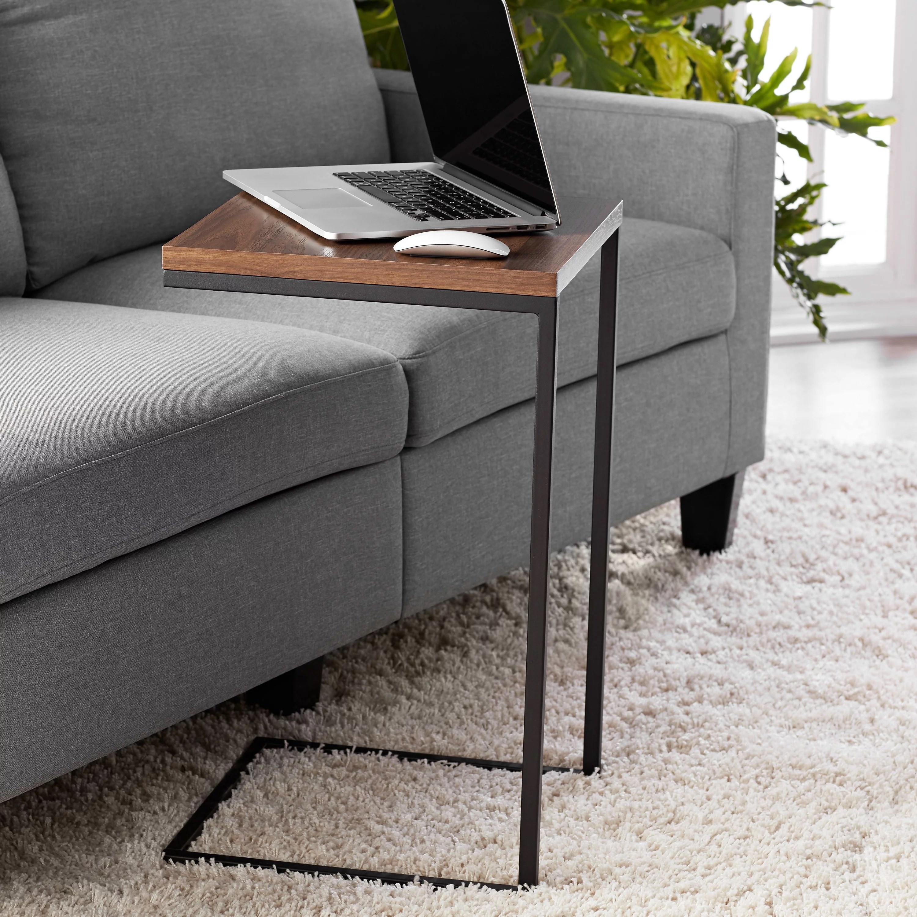 The C-shaped end table next to the couch with a laptop on it