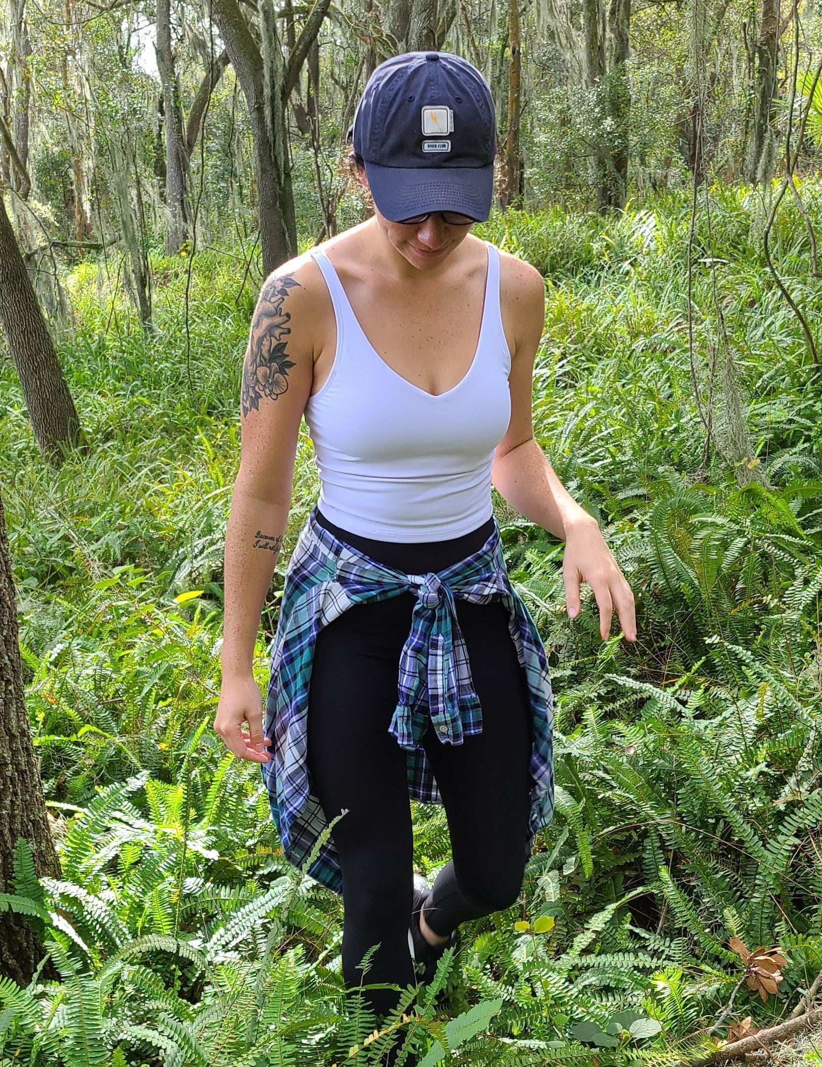 Reviewer hiking in the white crop top and leggings with flannel tied at waist
