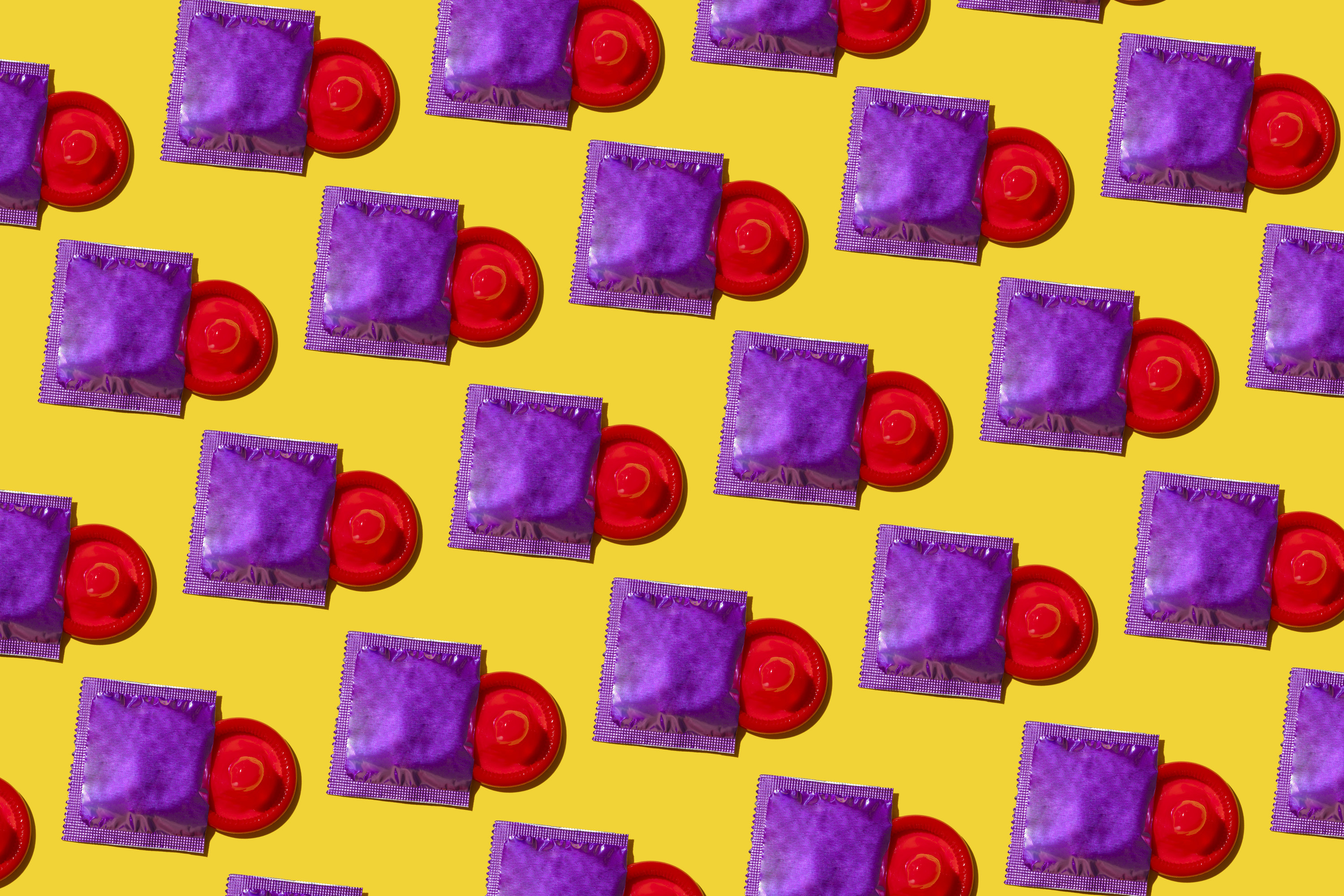 red condoms in purple wrappers on a yellow background