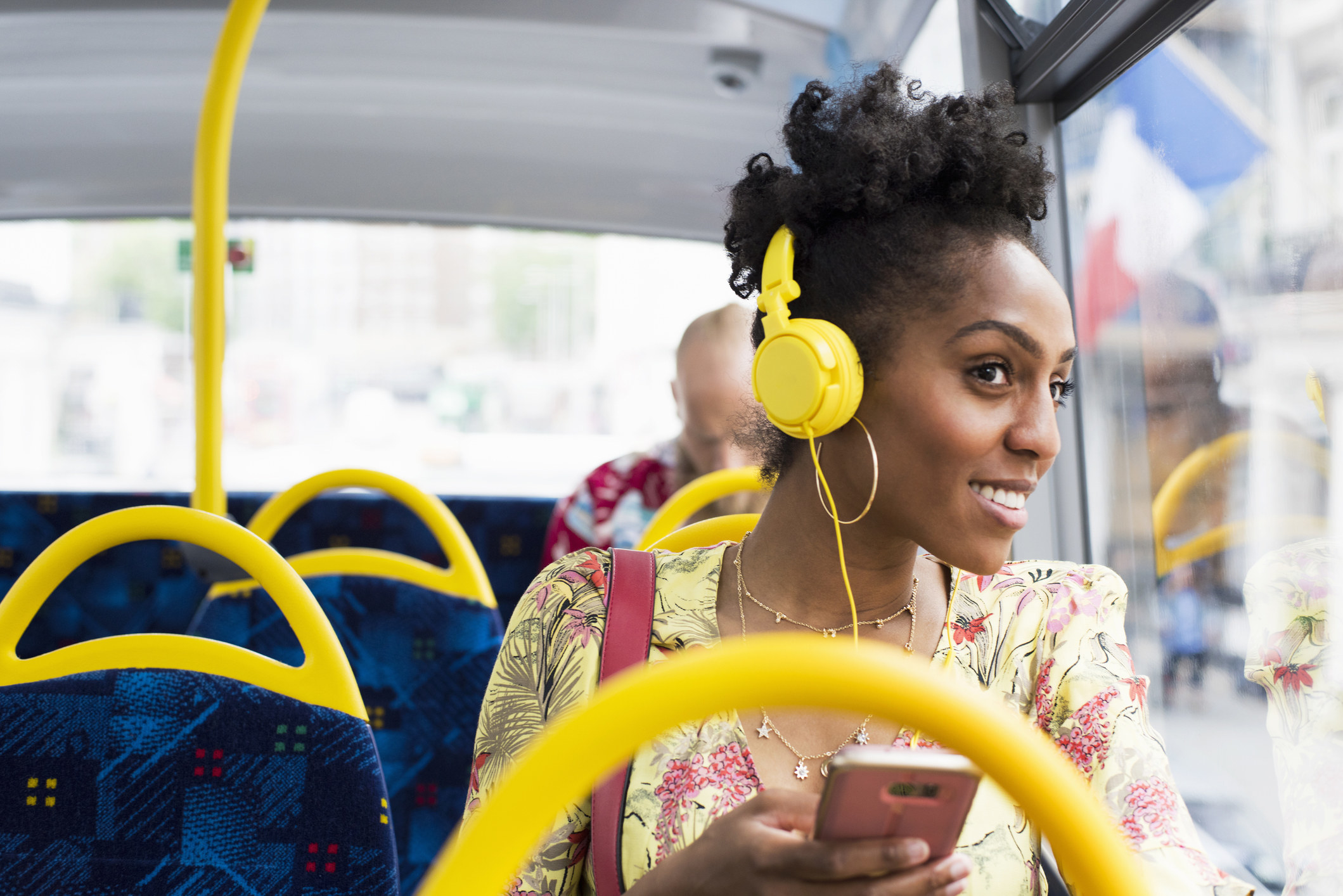 Woman listening to music on her phone through headphones while on the bus