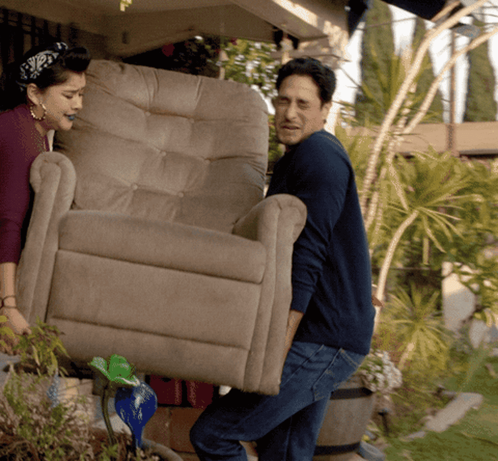 A man and a woman carry an armchair to their lawn