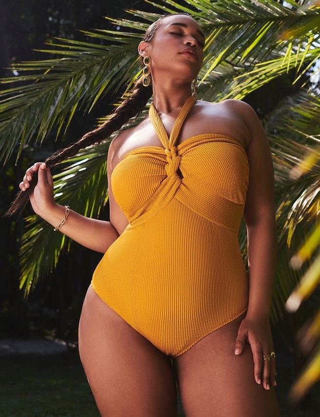 model in mustard yellow ribbed one-piece swimsuit with a knotted front and neck tie