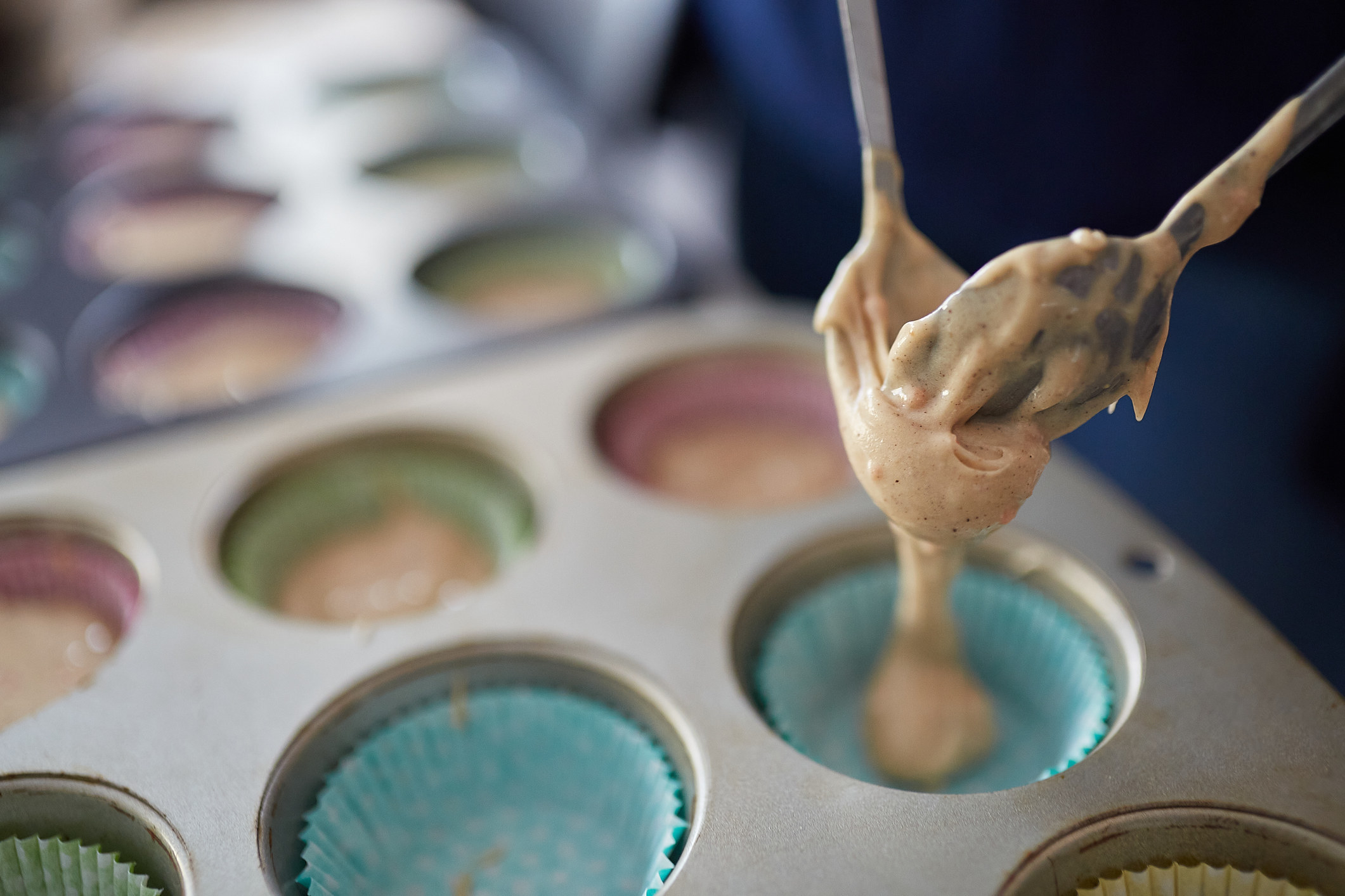 Cake mixure being spooned into a cupcake tin.