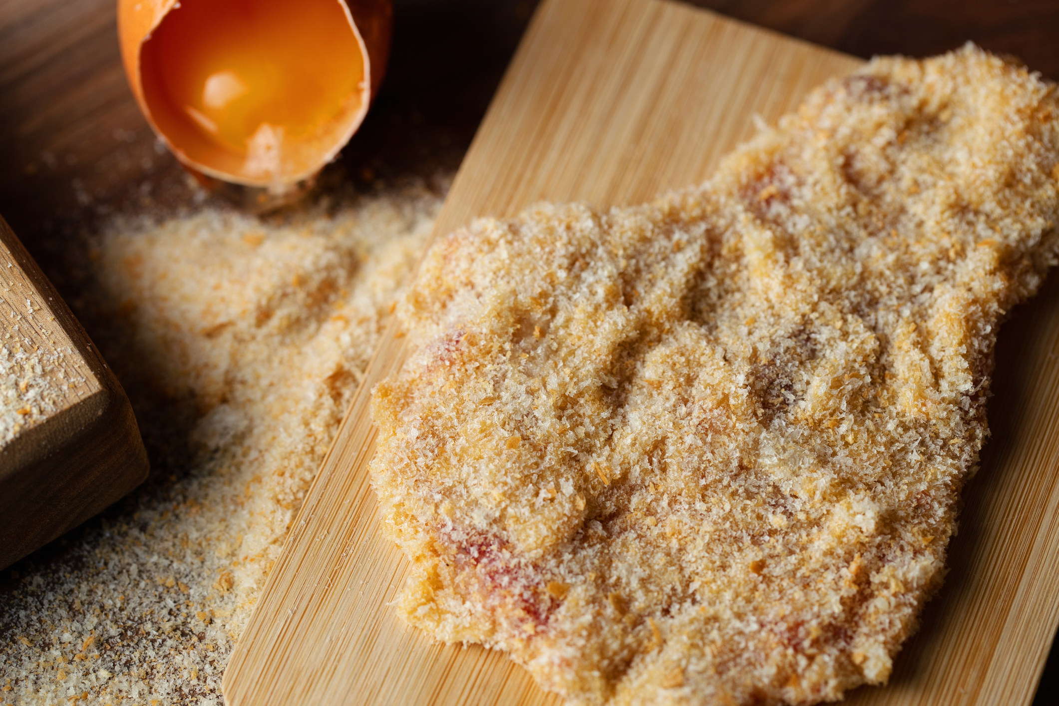 Breaded chicken cutlet on cutting board.