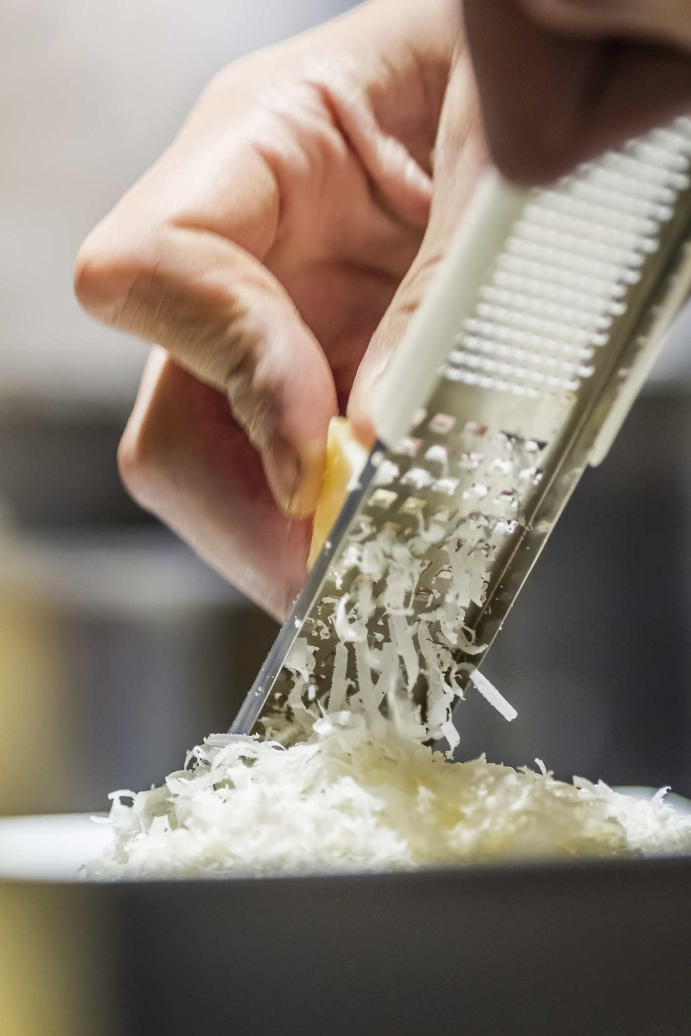 Close up of male hand grating parmesan cheese.