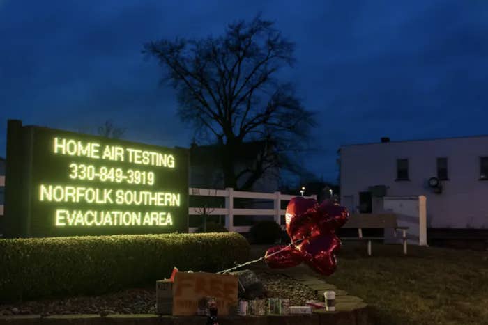 at night, red heart balloons sit next to a lit up sign that reads &quot;home air testing 330 849 3919 norfolk souther evacuation area&quot;