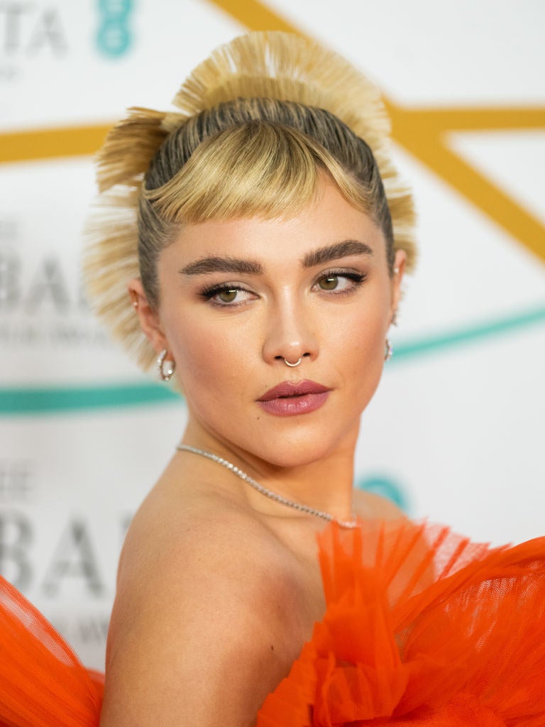 A closeup on Florence Pugh looking over her shoulder