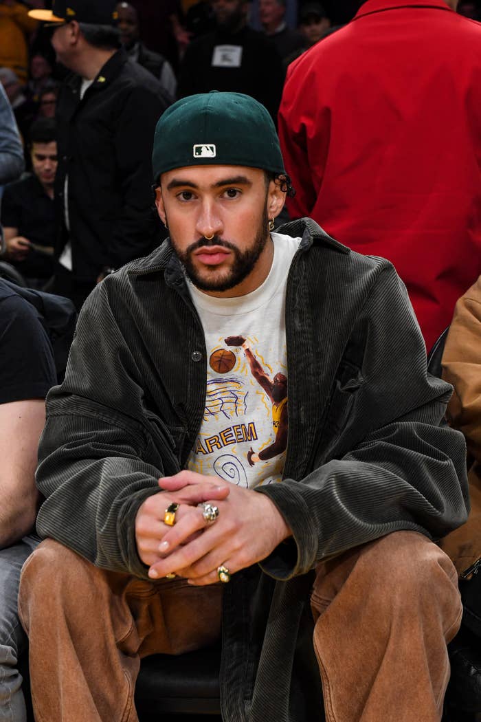 Bad Bunny looking straight ahead as he sits front row and a sports event