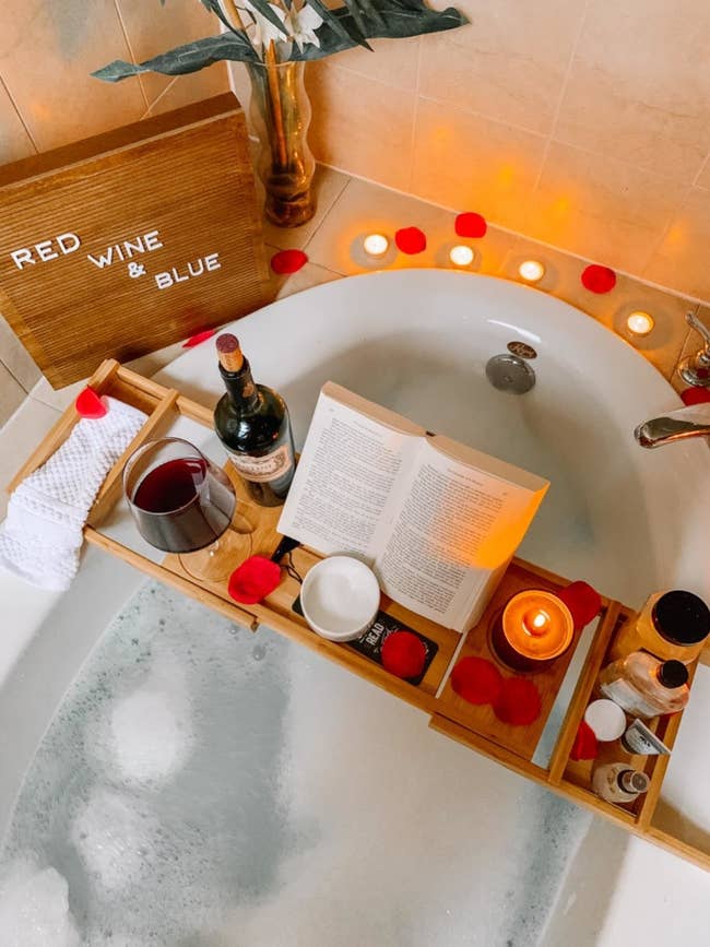 Reviewer image of a bath caddy with wine, candle, and a book on it