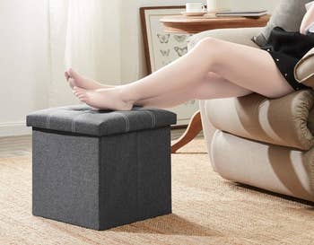 Model putting their feet up on the grey cube storage ottoman