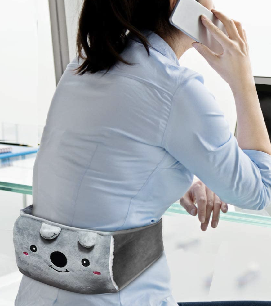 a person wearing the heating pad on their lower back while sitting at their desk