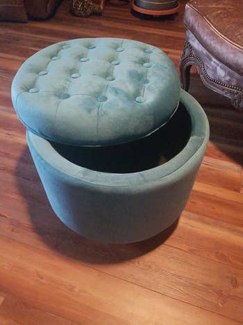 the blue storage ottoman with the lid pushed slightly to the side to show how much storage space is inside