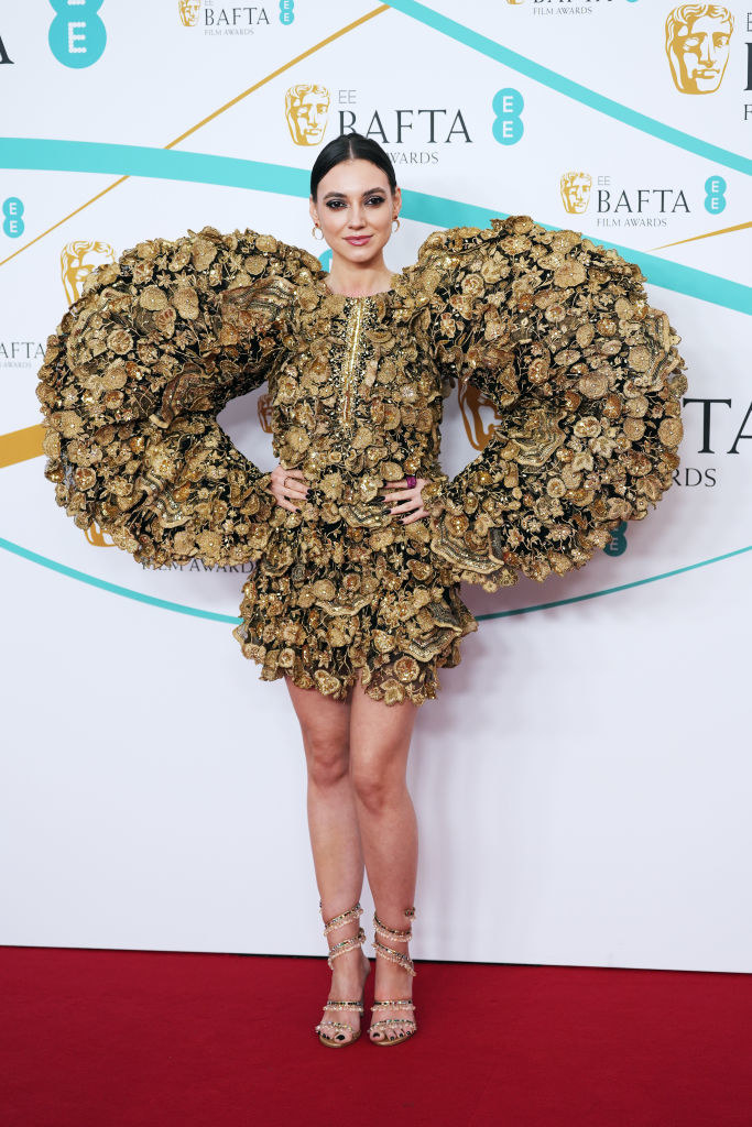 Andreea Cristea attends the EE BAFTA Film Awards 2023 at The Royal Festival Hall in a mini dress with elaborate puffed sleeves