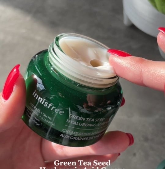 a person dipping their finger into an open jar of the green tea moisturizer
