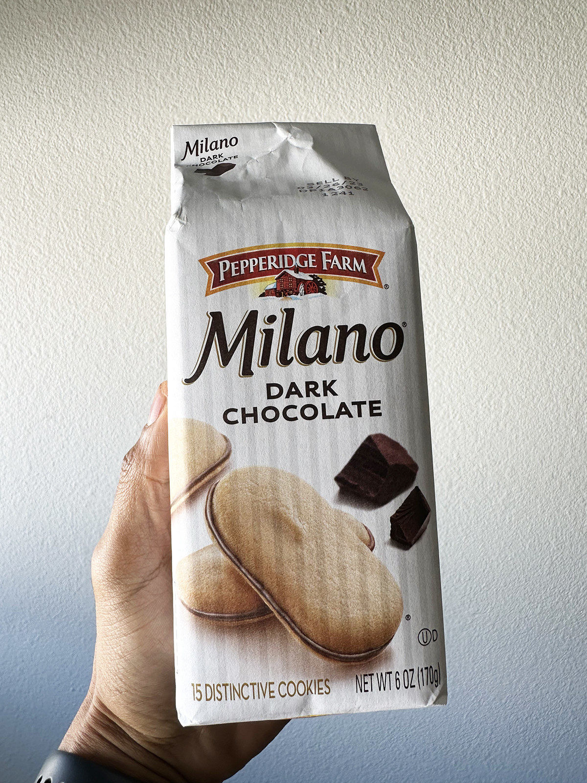 A hand holding a package of Pepperidge Farm Dark Chocolate Milanos