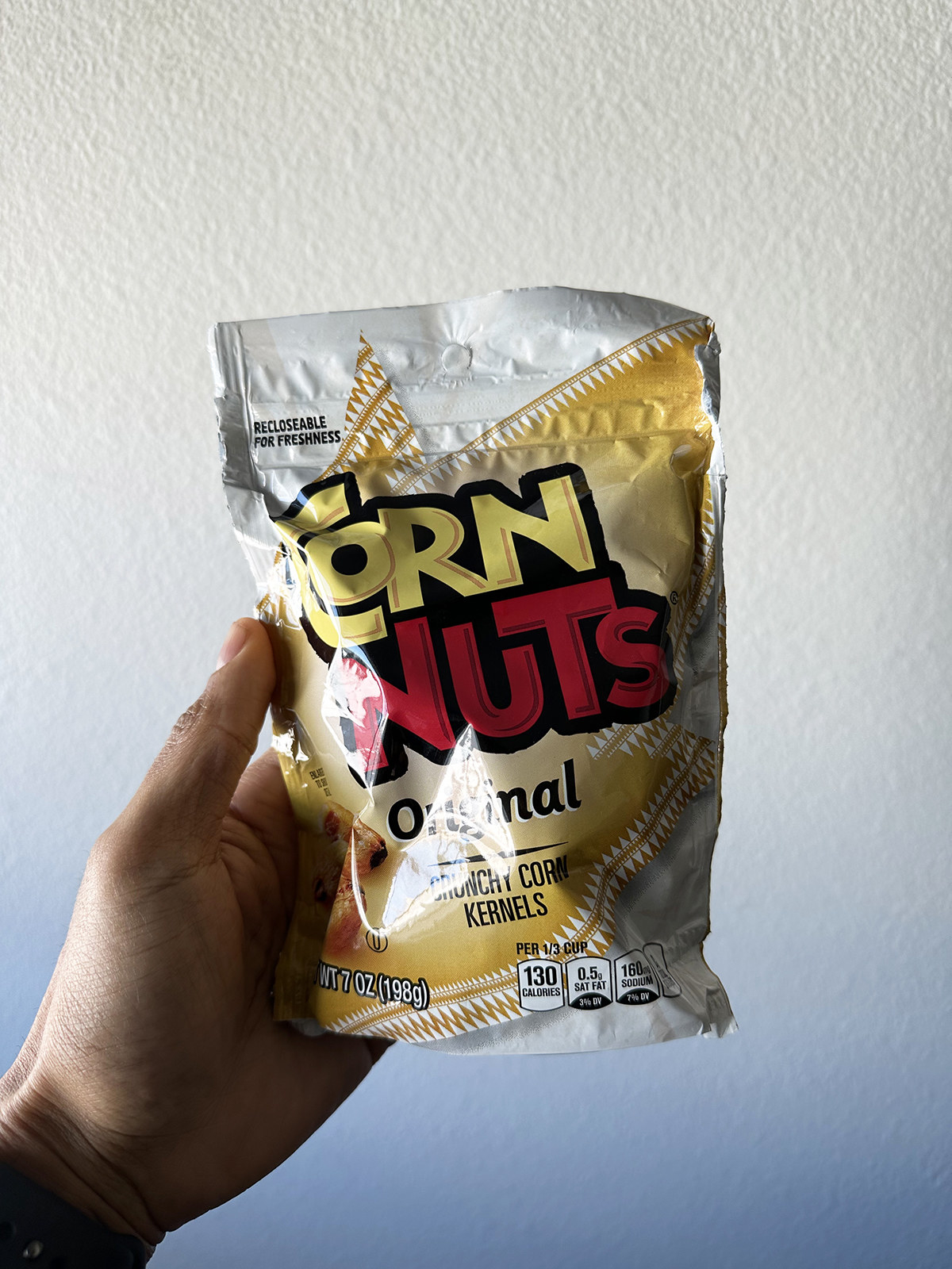A hand holding a pack of Corn Nuts Original Crunchy Corn Kernels