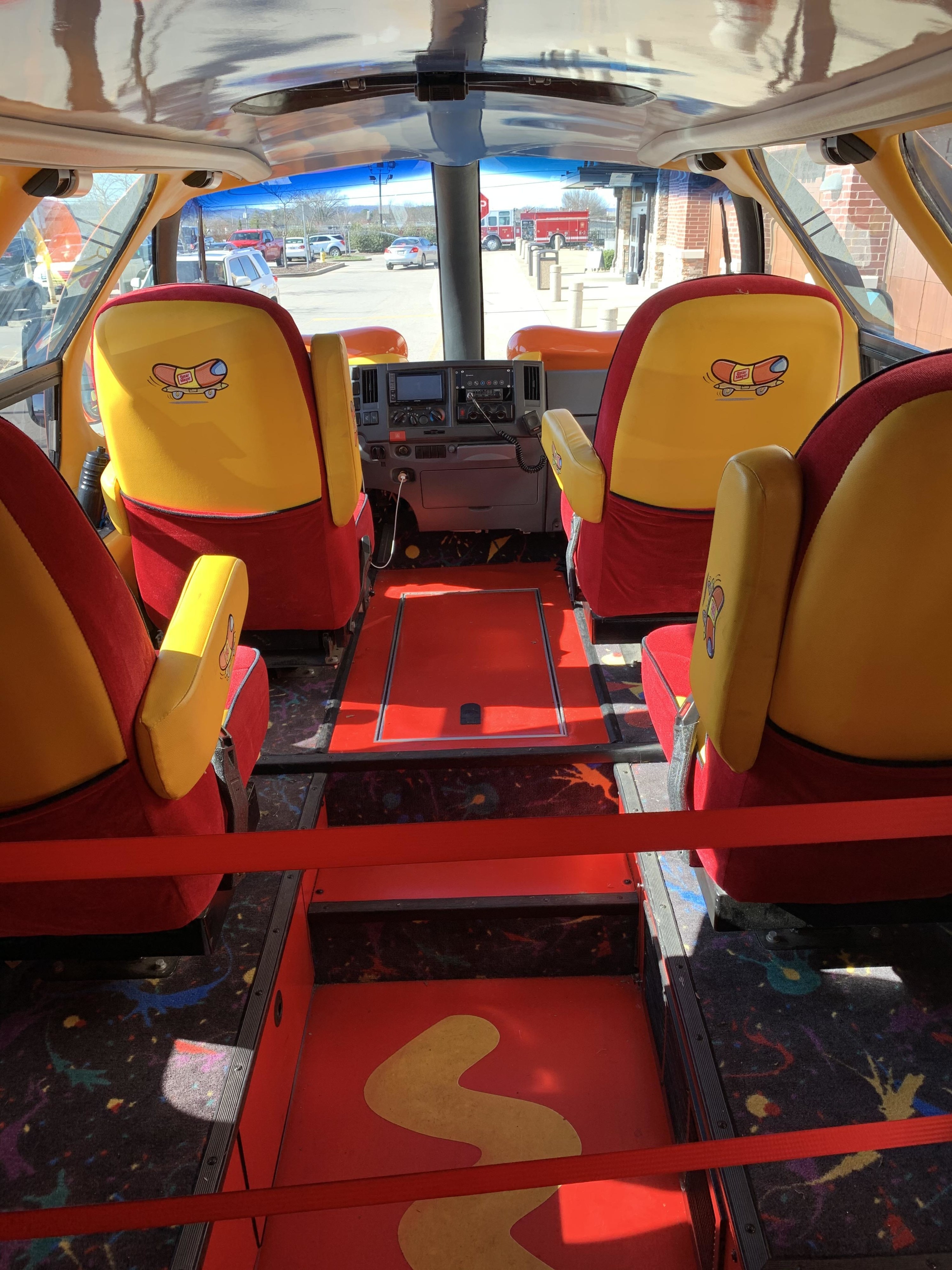 Brightly colored (red and yellow) seats with a yellow mustard zigzag on the floor and hot dogs illustrations on the backs of the seats