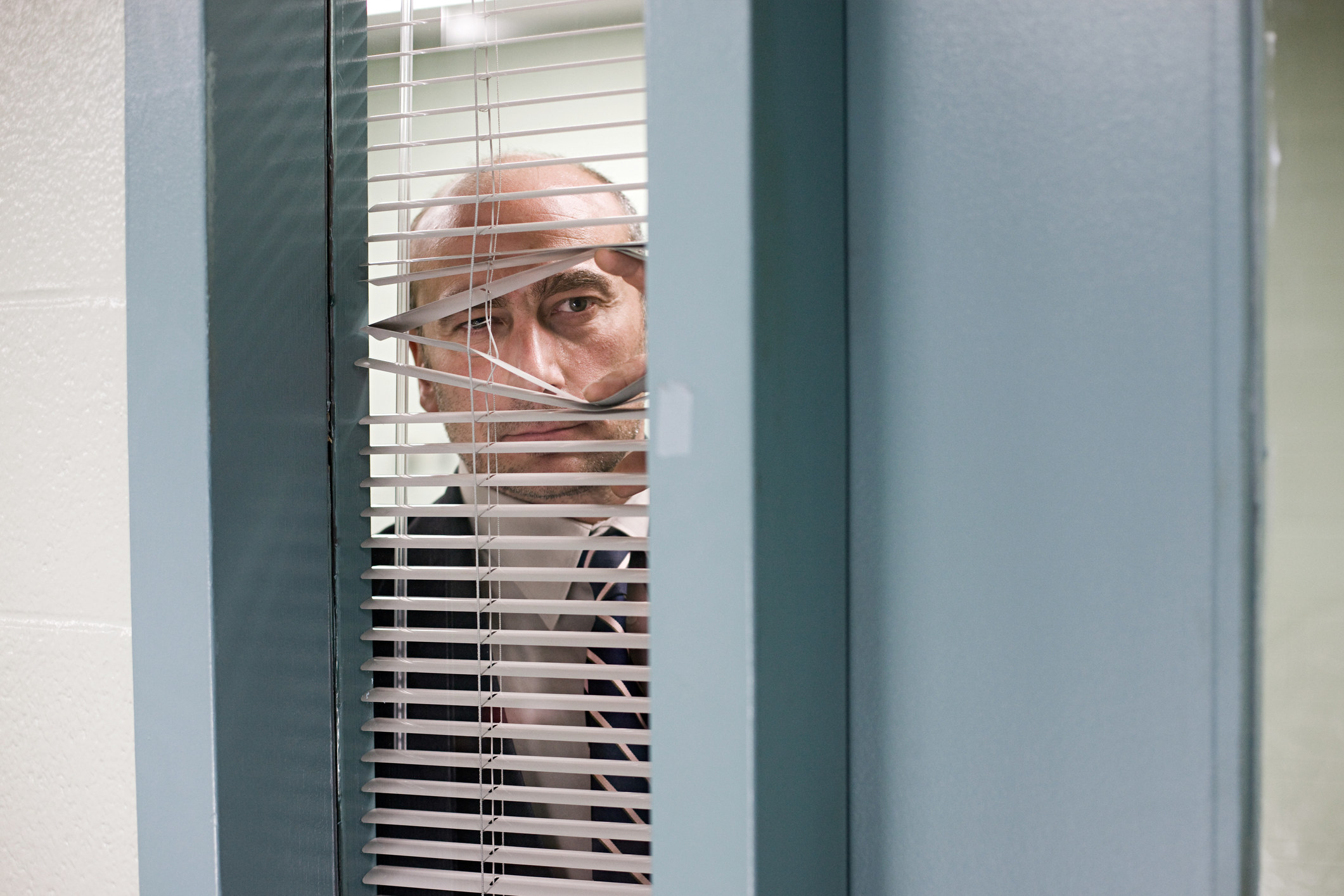 man peeking through blinds