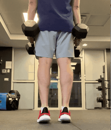 the author holding dumbbells and standing on toes