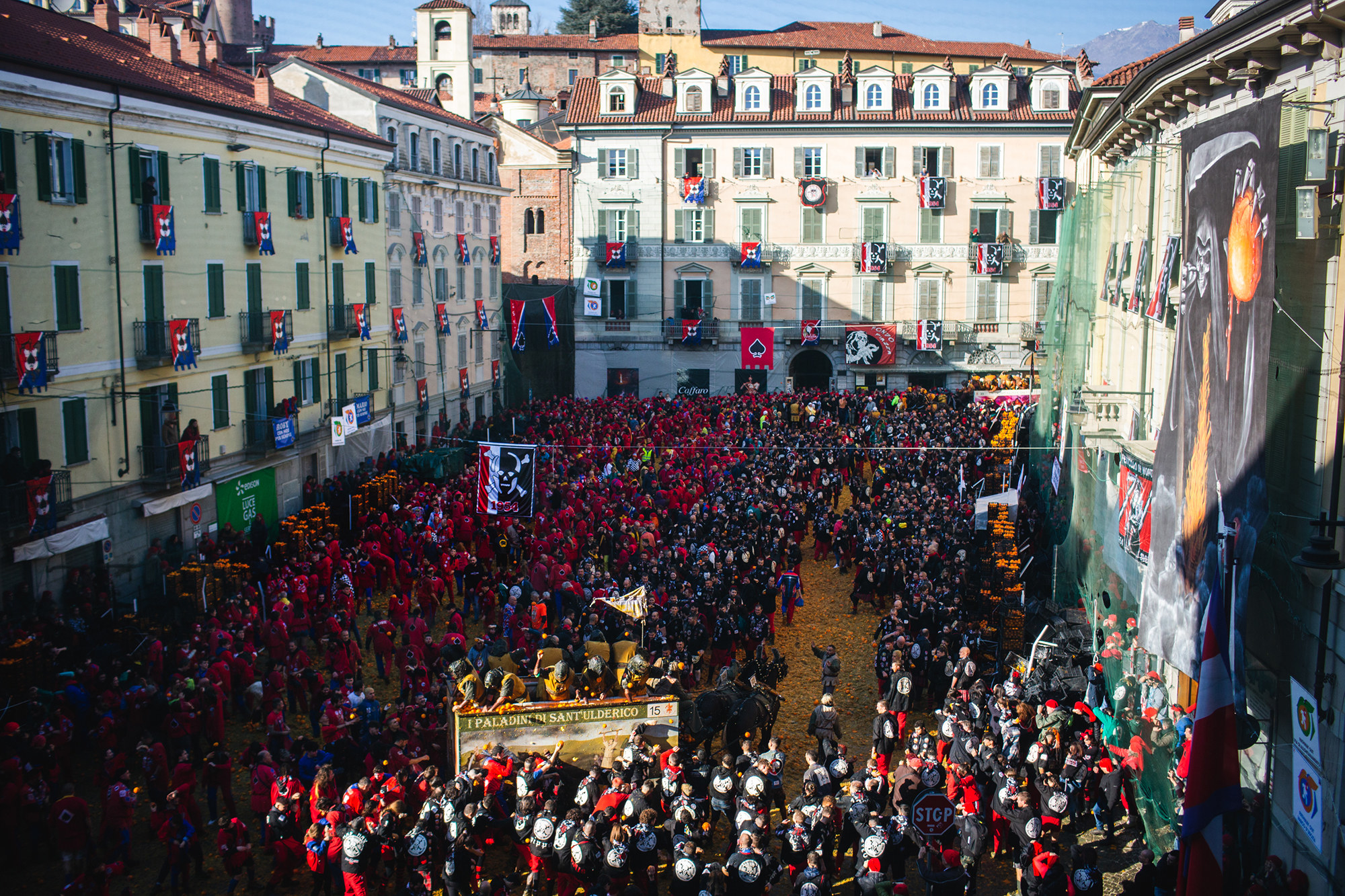 A public square is filled with people dressed in black and red medieval costumes.