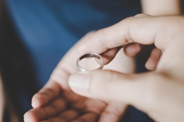 A close-up view of a young couple&#x27;s hands holding a wedding ring, a concept of divorce