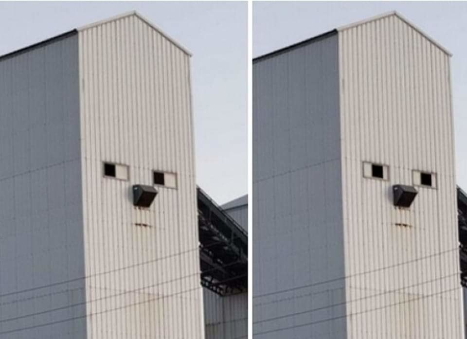 A silo building that has windows that make it look like eyes looking to the side