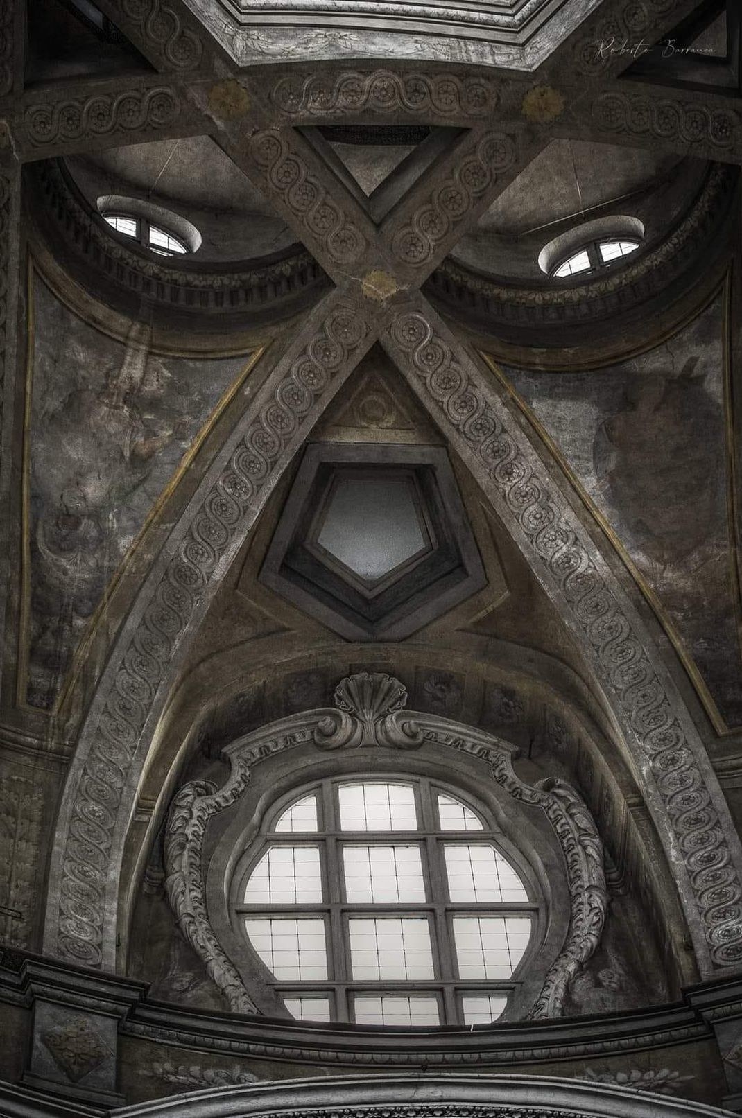 The inside of the church ceiling with arches and windows shaped like an angry face
