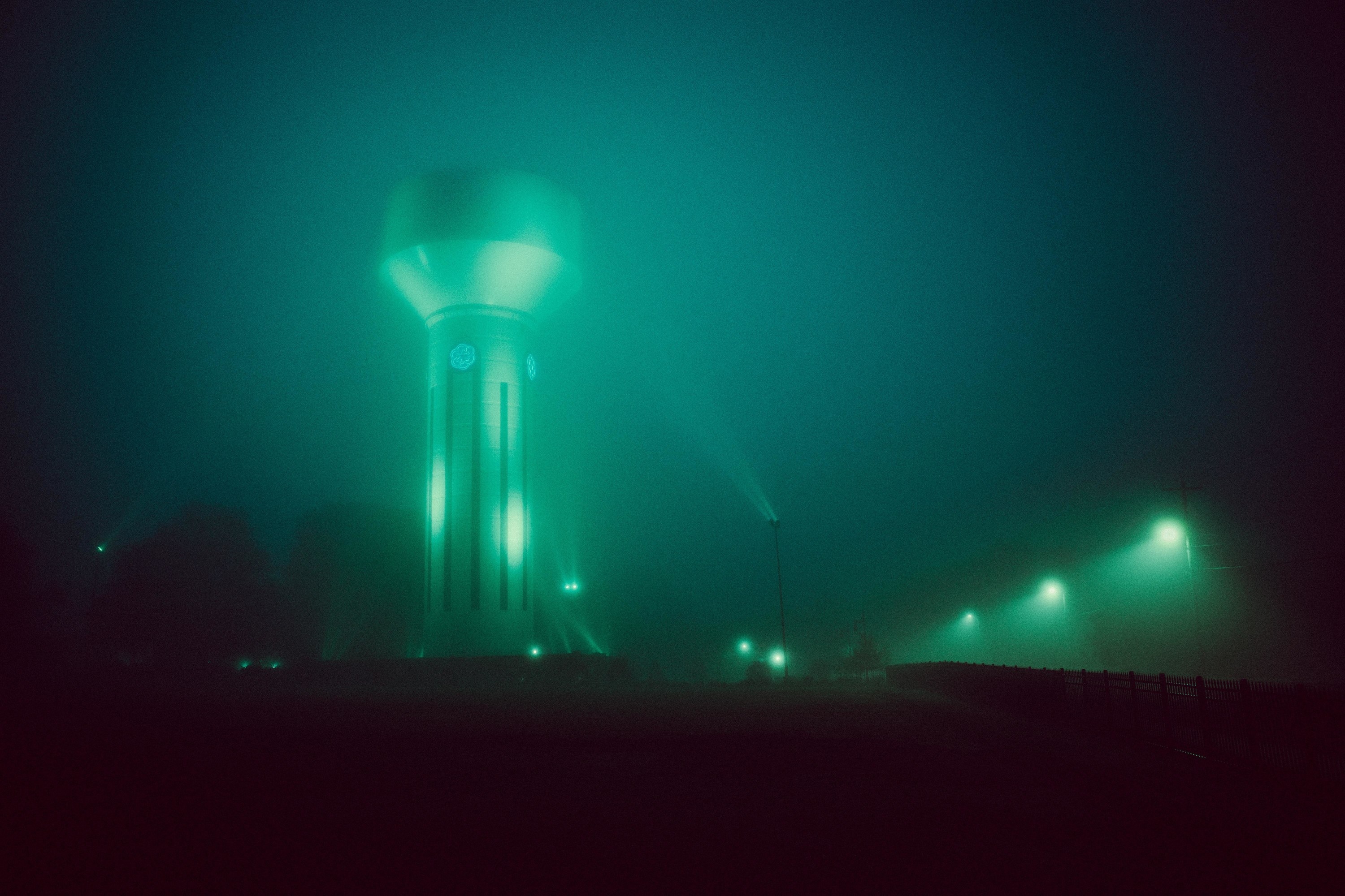 A water tower at night in the fog with eerie, alien-like lighting