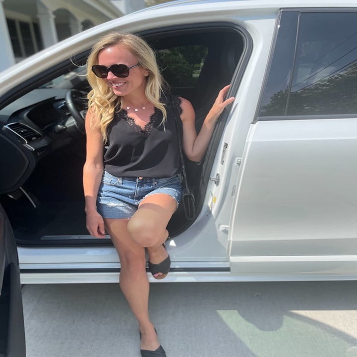 Reviewer wearing the top in black with a pair of denim shorts and black slides