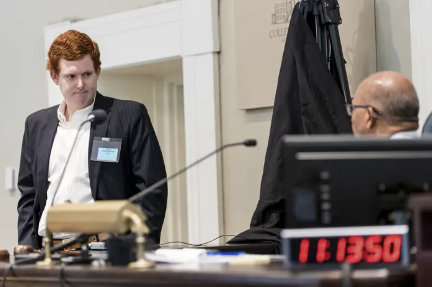 buster murdaugh stands in a suit giving testimony in a courtroom