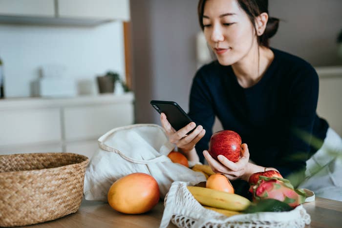 Woman looks at phone in kitchen