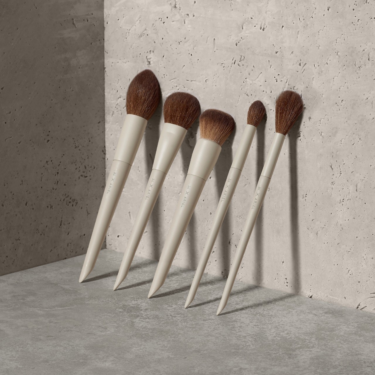 the five piece set of stylish brushes leaning against a concrete wall