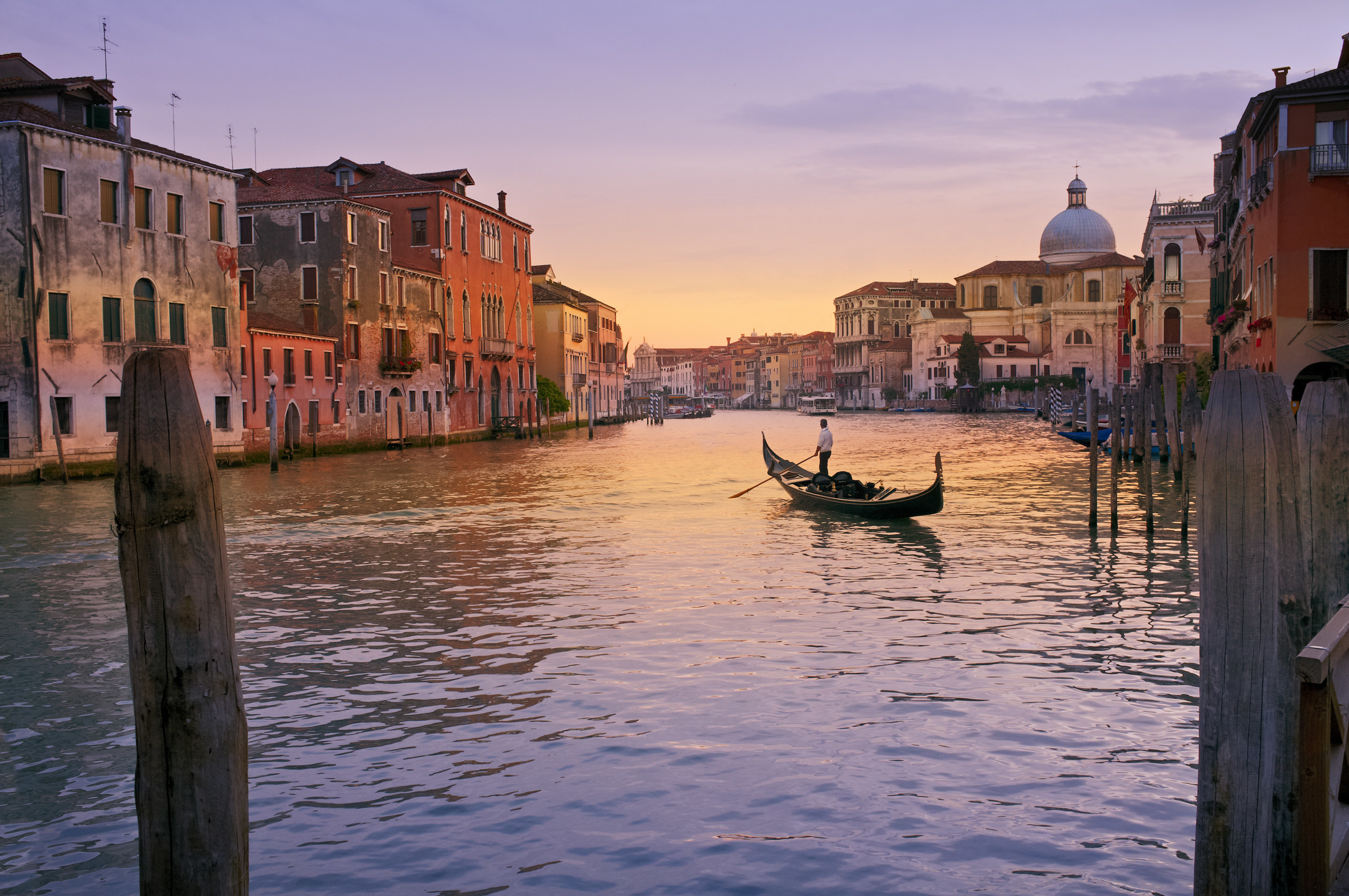 A man rowing a gondola on a canal in Venice.