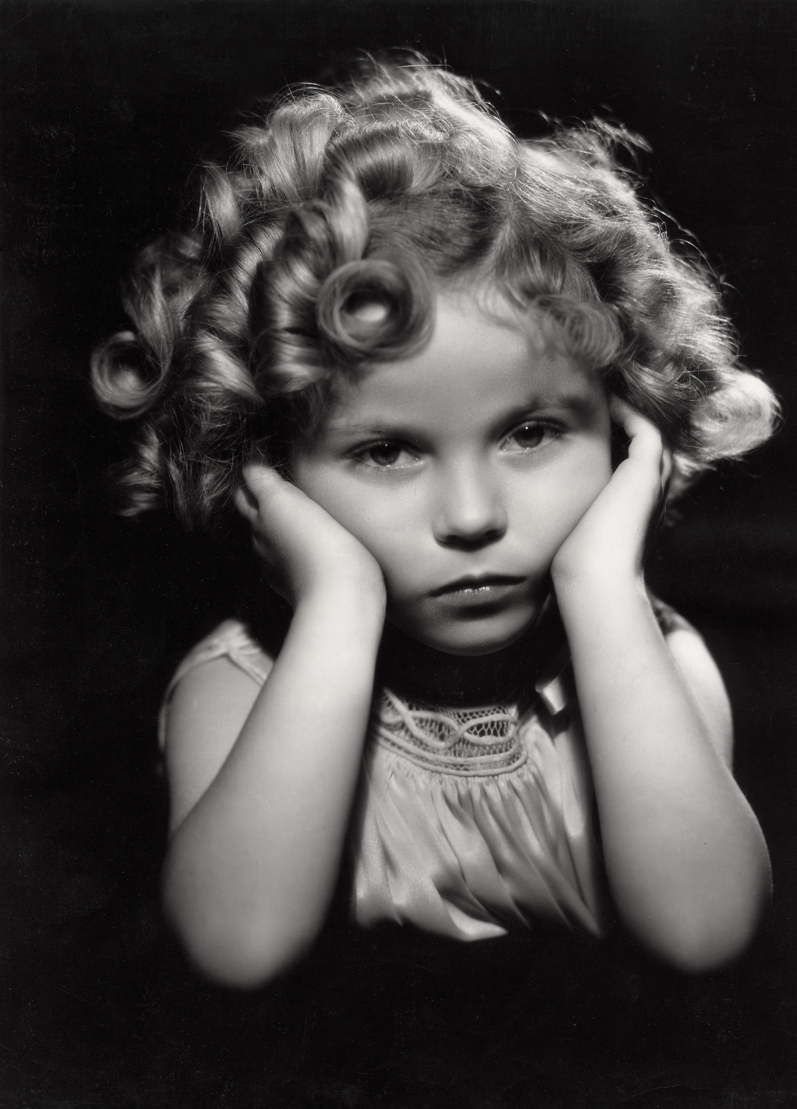 Shirley Temple posing with her head in her hands