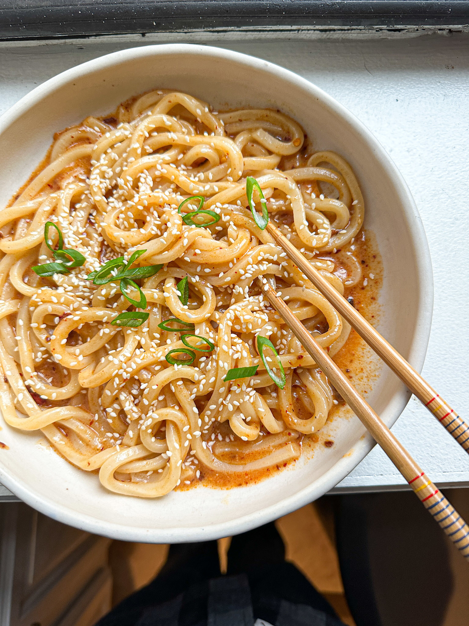 udon noodles in a bowl with scallion and sesame seed garnish
