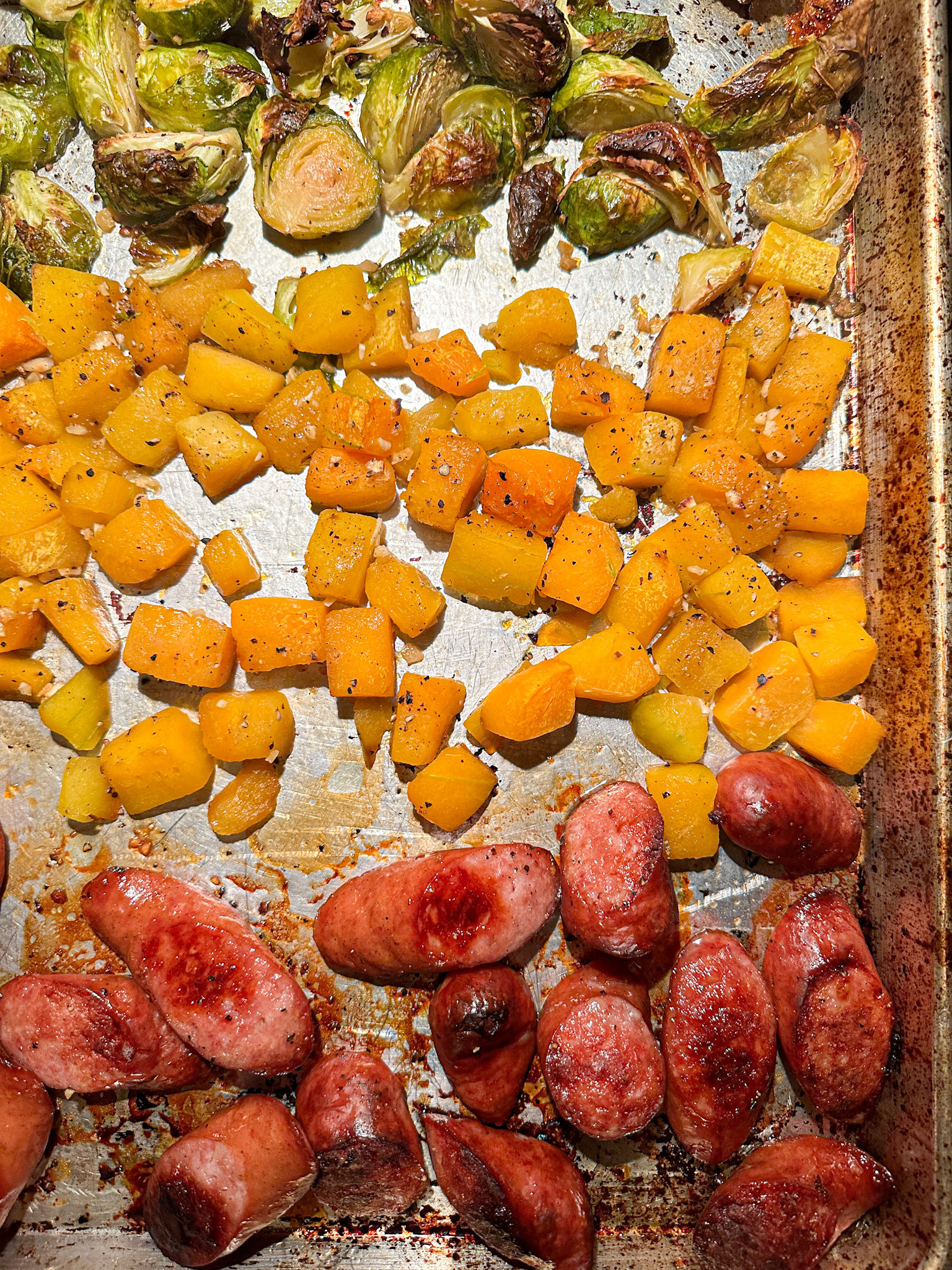 sausage, squash, and brussels sprouts on the sheet pan, after they&#x27;re done cooking and golden brown