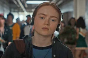 Max from Stranger Things walking through the school hallway with headphones on