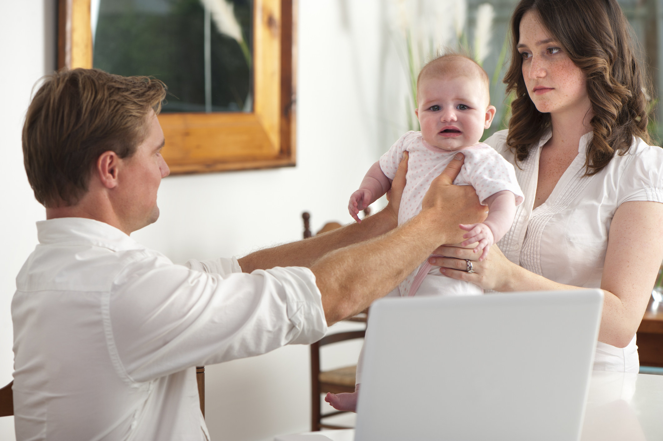 Man handing off his baby to his wife