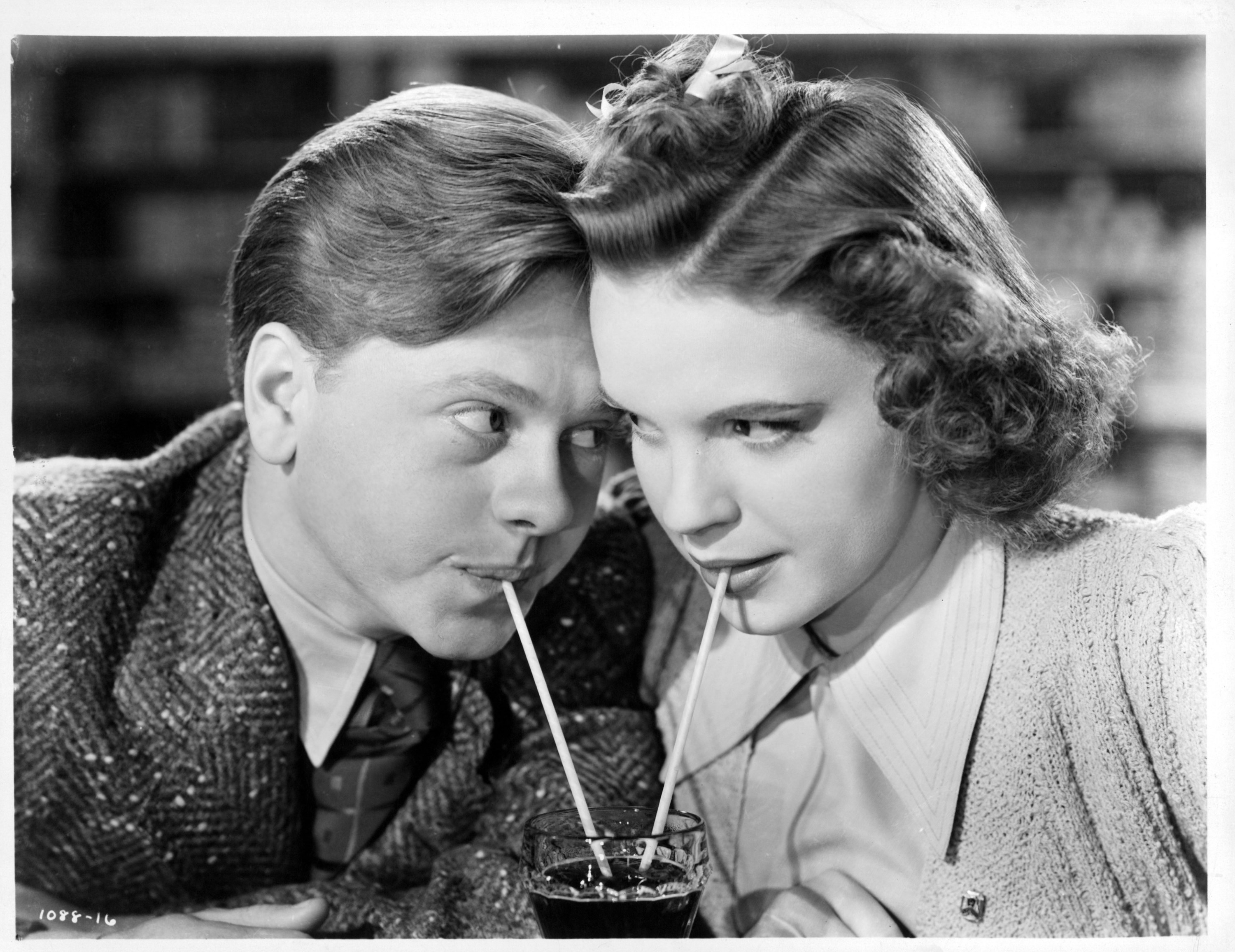 Mickey Rooney and Judy Garland sharing a soda together as they stare into one an others eyes in a scene from the film &#x27;Babes In Arms&#x27;