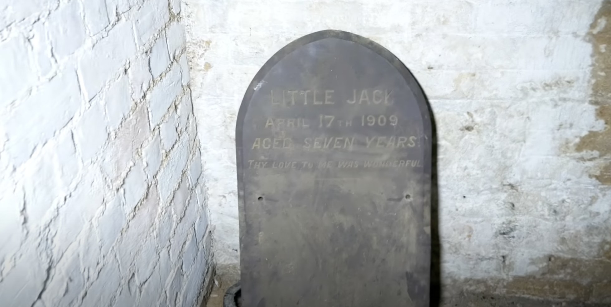 A tombstone in the corner of a room inside of an abandoned building