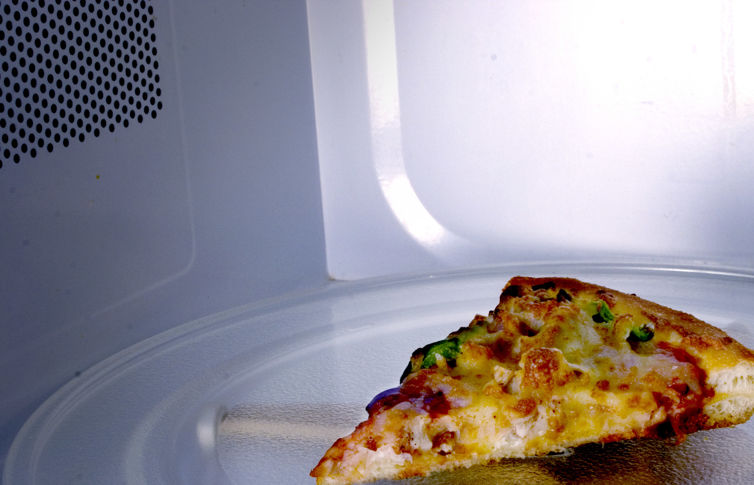 A slice of pizza in the microwave.