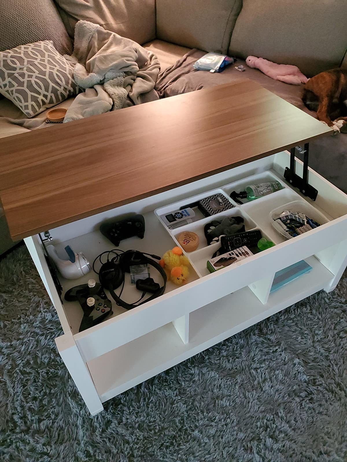 White coffee table with wooden hood being lifted up to reveal storage inside