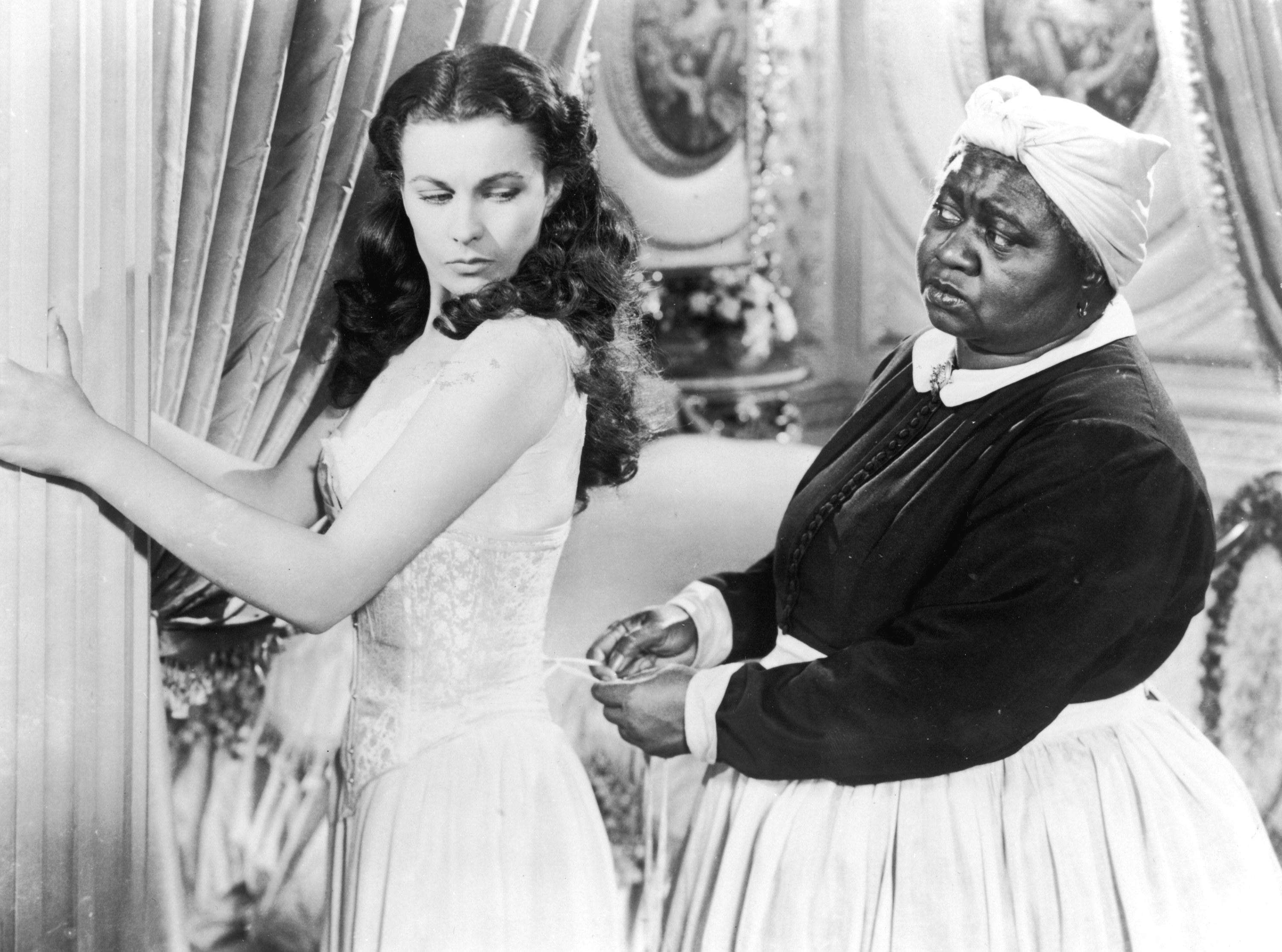 Vivien Leigh holds onto a pillar as Hattie McDaniel tightens her corset in &quot;Gone with the Wind&quot;